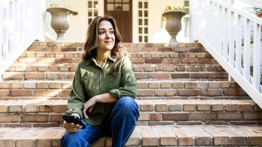 Woman with phone in front of a suburban house