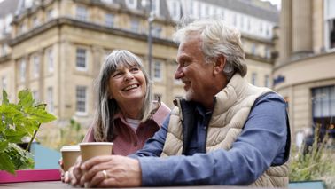 A happy senior couple enjoying a moment together seated at an outdoor city cafe.