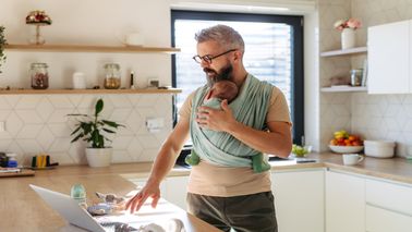 Dad baby wearing while standing in the kitchen working