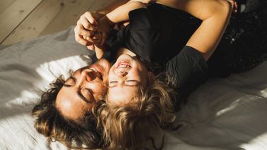Happy mother and daughter having fun and playing together on the bed at home.