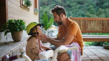 A loving dad preparing his daughter for a bike ride.