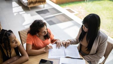 Female professional consultant talking to a mother and daughter during a home visit 