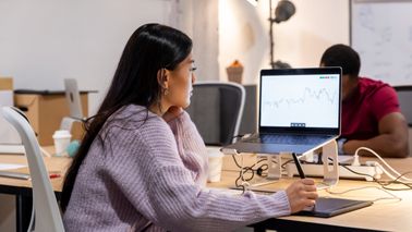 Woman tracks economic and market movements on her computer in a modern office.