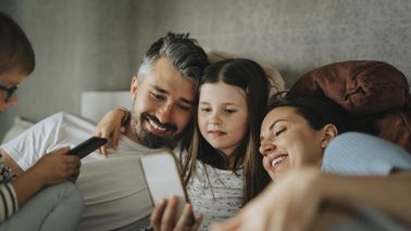Happy family enjoying watching smart phone at home