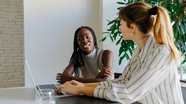 Two formal businesswomen collaborate during office meeting, discussing finance and the importance of a long-term financial plan with Northwestern Mutual