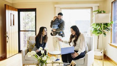 Wide shot of family discussing home for sale with real estate agent