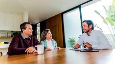 Couple talking to real estate agent at house