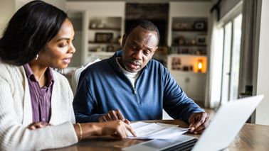 Husband and wife looking at laptop in kitchen