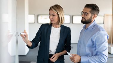 Two colleagues discuss strategic business plan in modern office