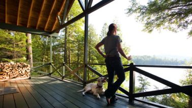 Woman with a dog looking at lake from her porch. 