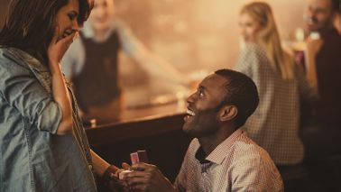 Man proposing to woman in a bar.