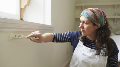 Woman painting with brush doing home improvement project