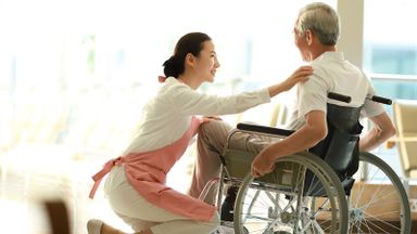 Home health aide helping man with the activities of daily living