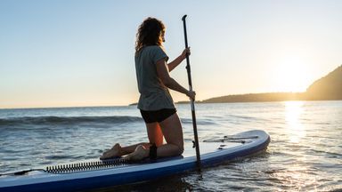 Woman paddleboarding at sunrise celebrating financial freedom with Northwestern Mutual