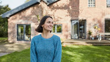 woman standing in front of hosue thinking about good debt vs. bad debt