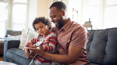 father and son playing ukulele on sofa