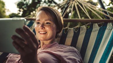 Woman in a hammock on a tablet reading about bond funds.