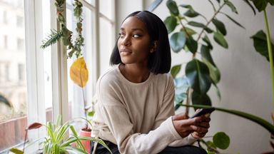 Woman looking out the window thinking about a savings account.