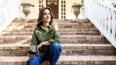 Woman with phone in front of a suburban house