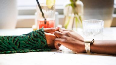 Two individuals holding hands across a table