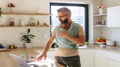Dad baby wearing while standing in the kitchen working