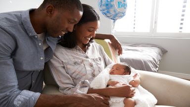 parents at home smiling at their newborn baby in the nursery