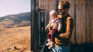 Father holding his new baby and contemplating if Trump Accounts could fit into his financial plan.