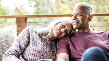 Couple having coffee and embracing on back porch of vacation home - stock photo