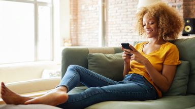  Young woman text messaging through smart phone. 