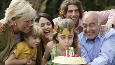 Young girl celebrating birthday with family and cake