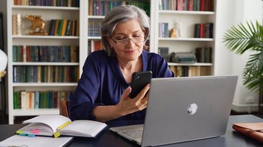 Woman contemplates financial returns on laptop in book-lined office