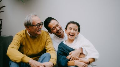 Cheerful young girl having fun with her grandfather and father