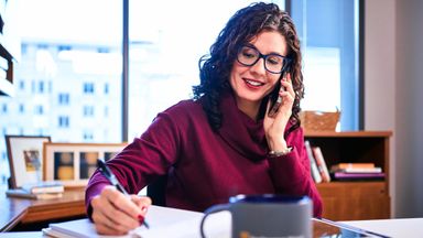 Woman financial advisor talking on the phone and taking notes