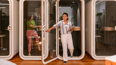 Co-workers use private booths in modern office