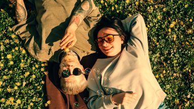 Young couple lying on grass blowing soap bubbles 