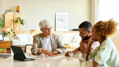 Mature female advisor discussing with couple in apartment.