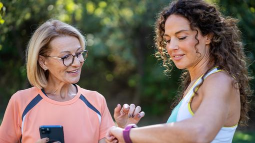 Two women talking and jogging in the public park. 