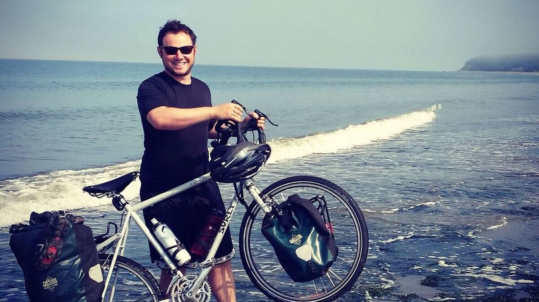 man standing on beach with bike