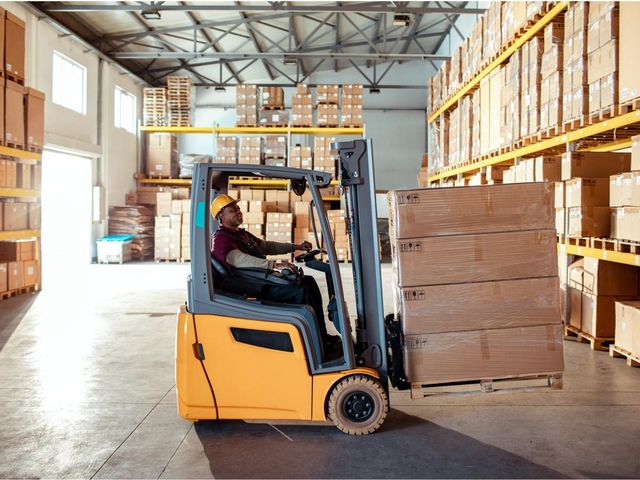 Forklift loading inventory in a warehouse.