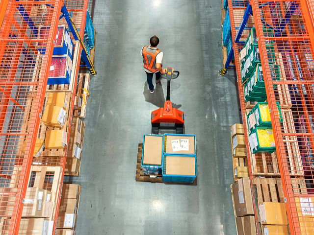 warehouse worker moving items with pallet jack