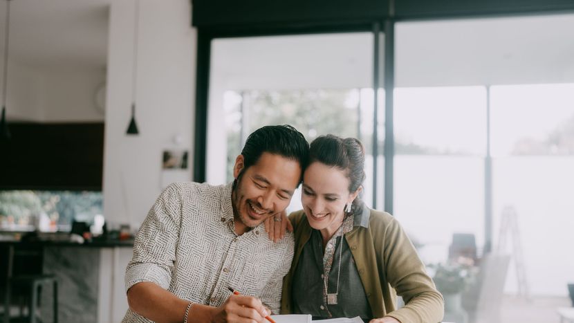 Cheerful couple looks at paperwork together in a kitchen