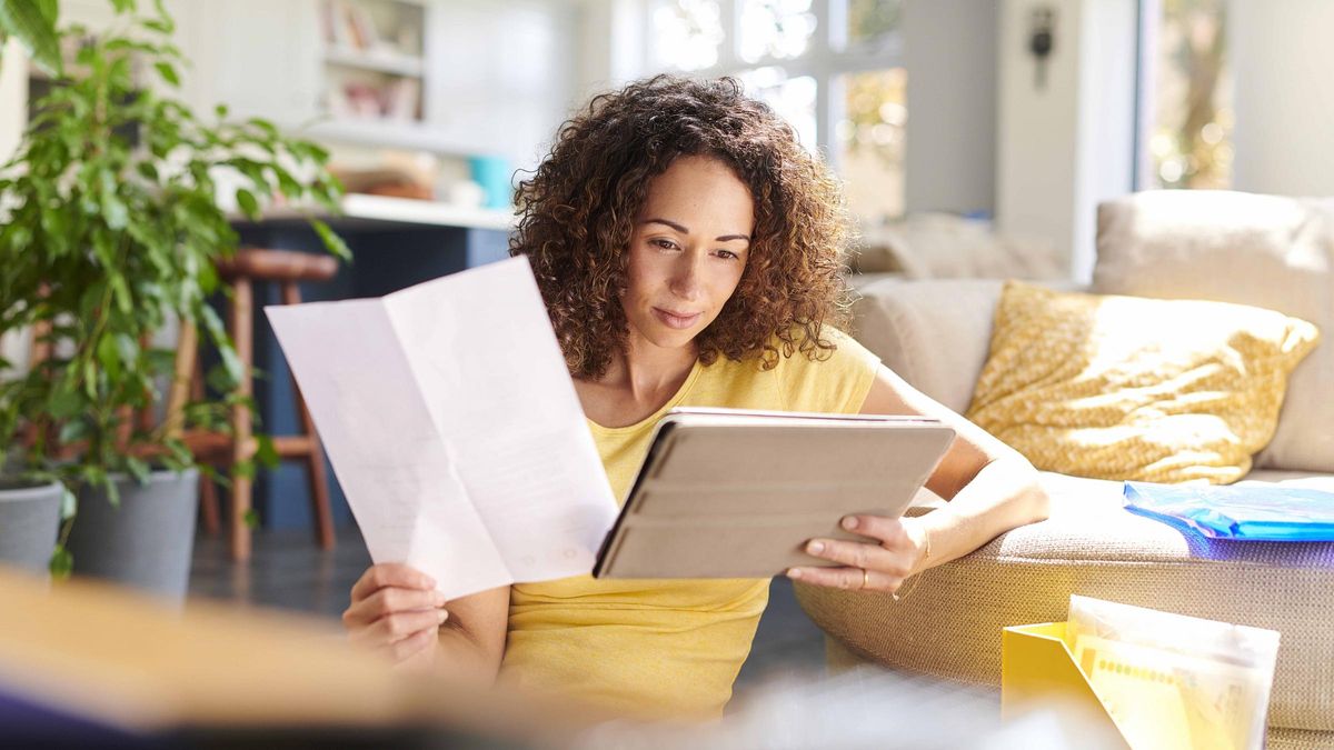 woman looking at tablet deciding to pay debt or start investing