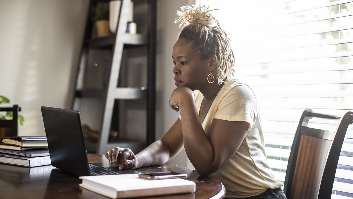 Woman at a desk at home looking at a laptop reading about asset classes by risk.