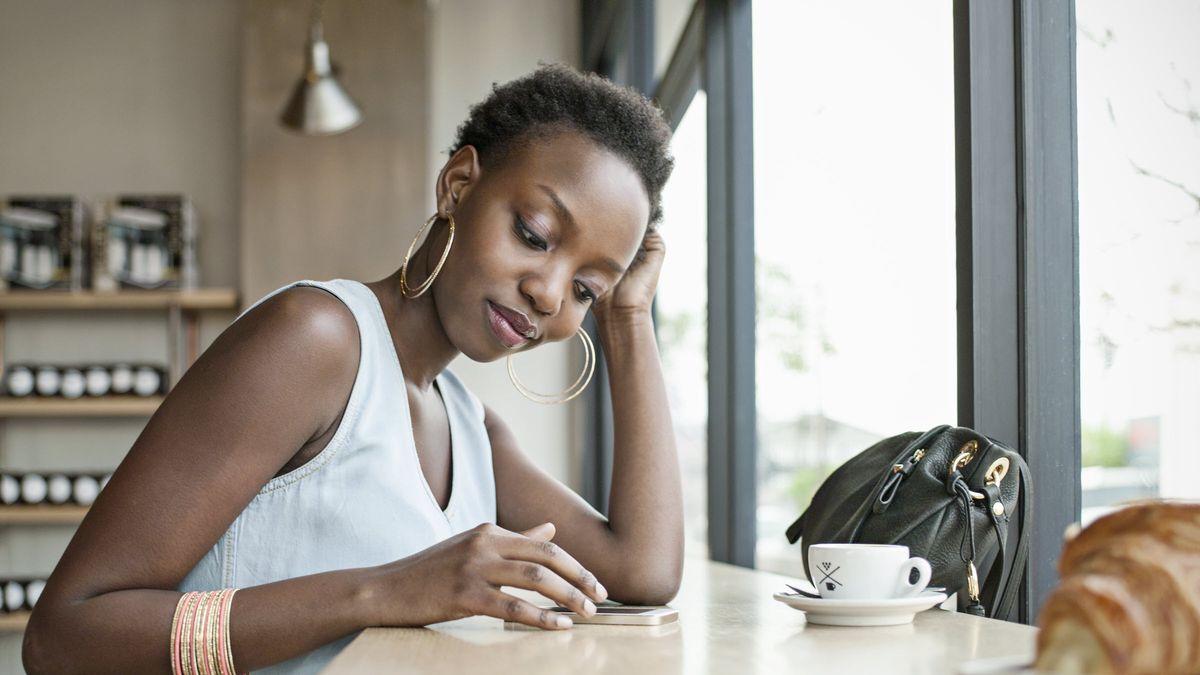 Woman sitting at a table and drinking coffee while learning about the basics of investing