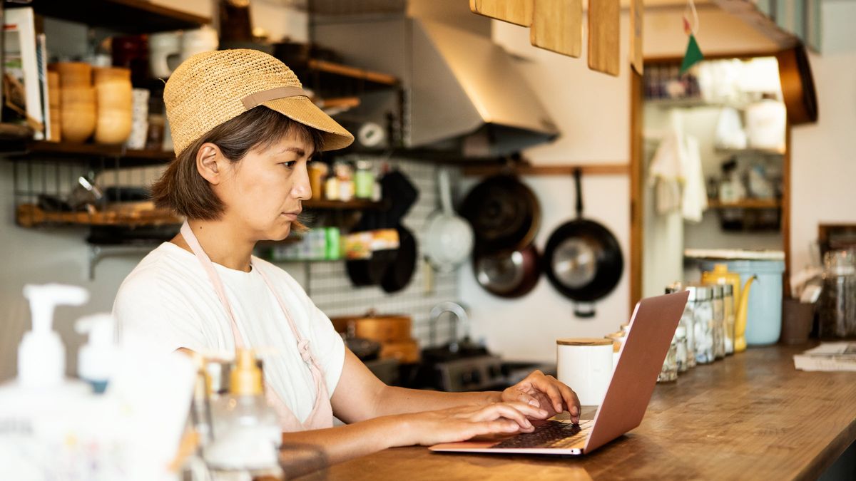 Woman in a restaurant looking at a computer learning about saving for retirement without a regular income.