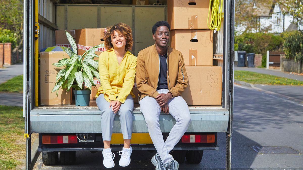 young couple sitting in back of moving van