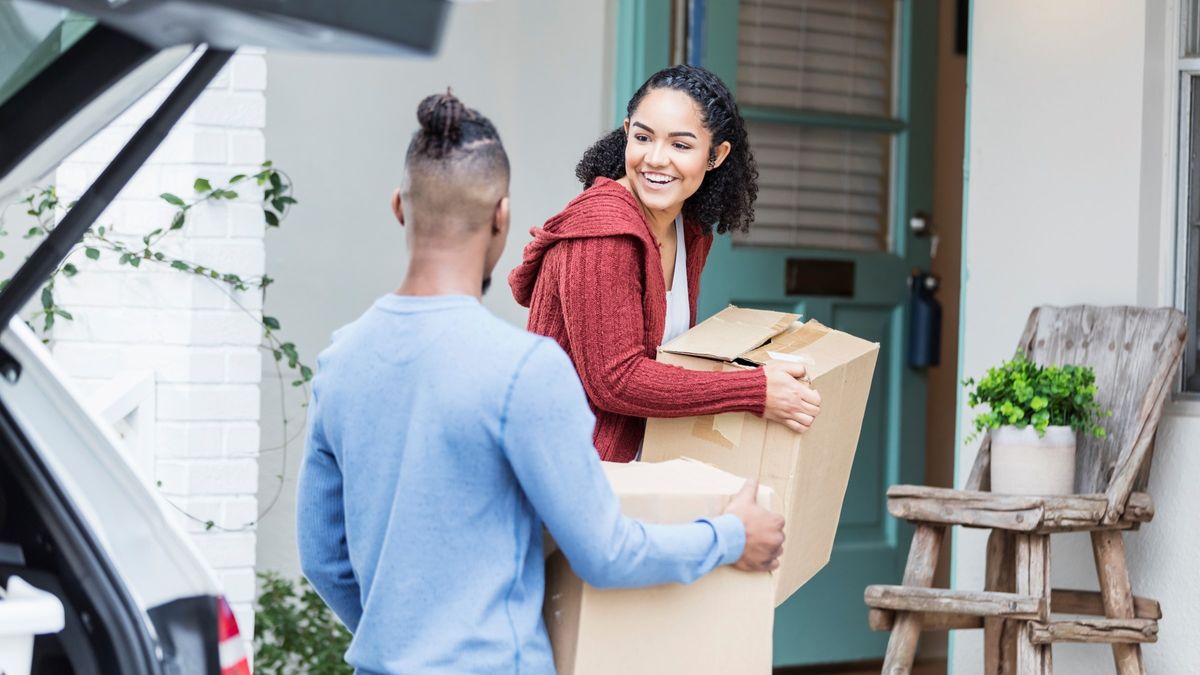 Couple carrying boxes into new house