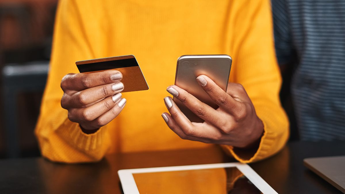 Woman looking at her phone and using her credit card