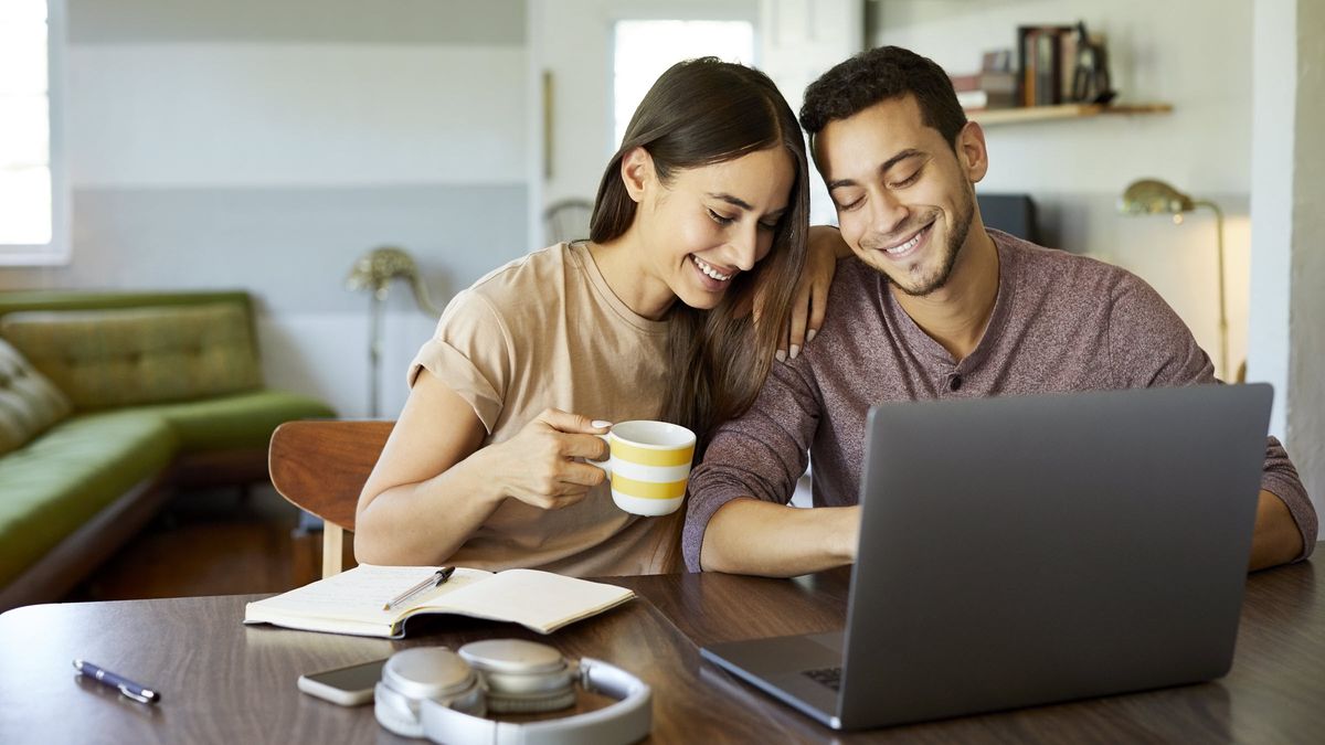 Couple at a table looking at a computer thinking about 5 ways to improve their finances in February.