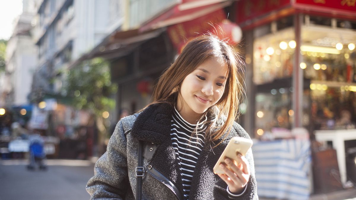 Woman outside looking at her phone reading about how to improve her finances in April